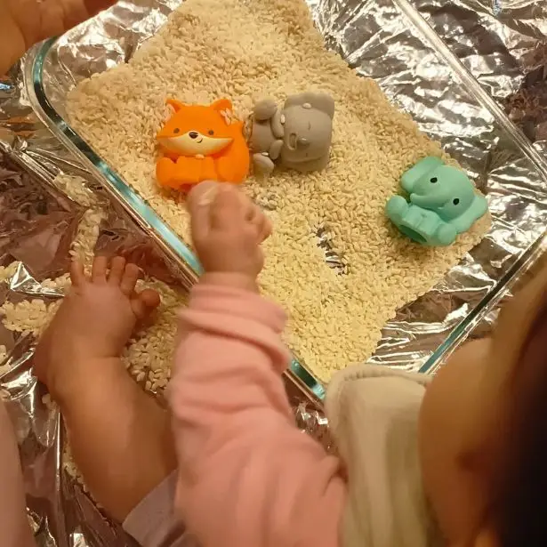 Un bambino di pochi mesi che gioca con del riso presso il laboratorio della Puericultrice Lombardia - Sara Moroni