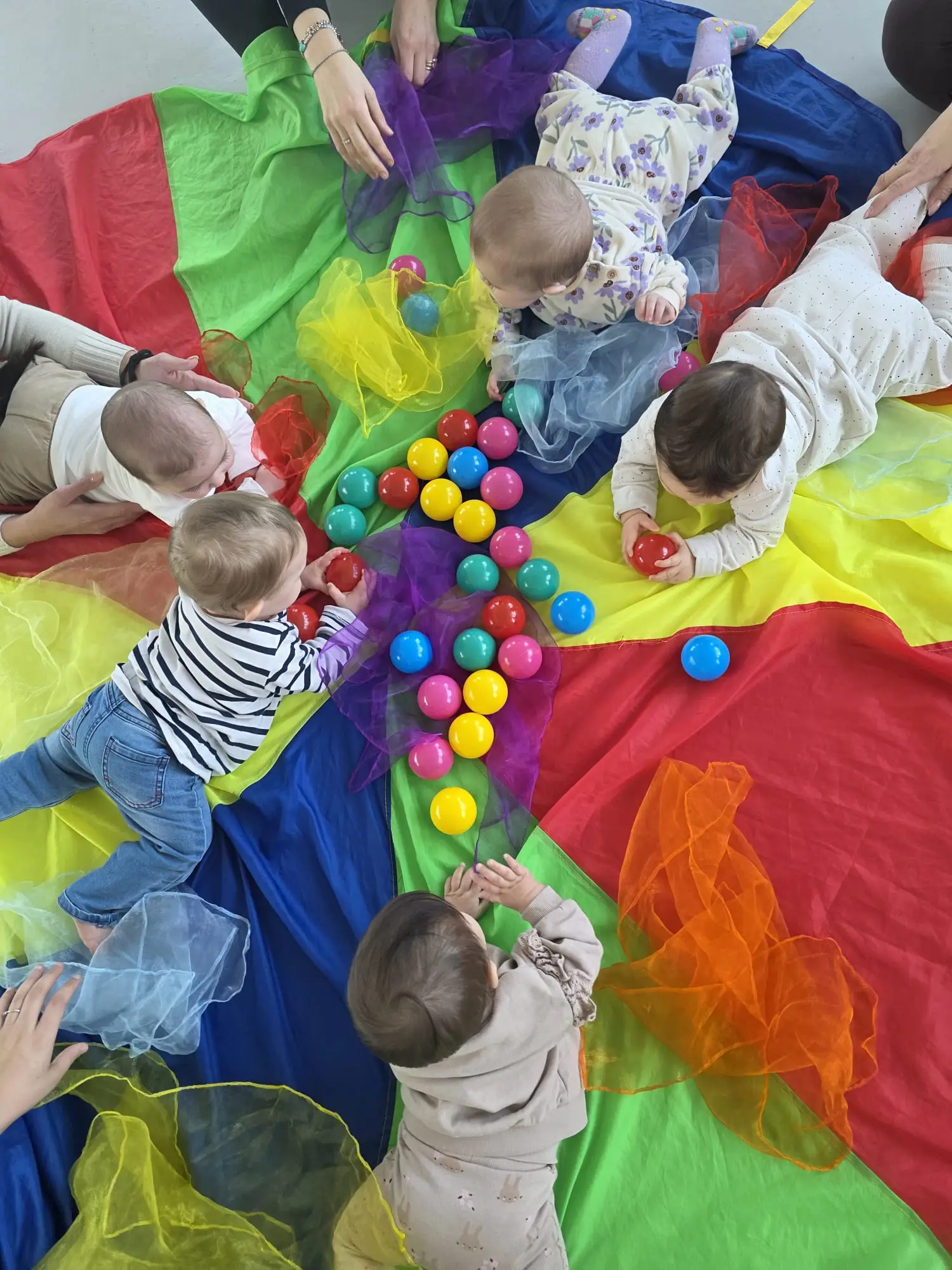 Un gruppo di bambini piccoli che giocano stesi su tappetini colorati presso il laboratorio della Puericultrice Lombardia - Sara Moroni
